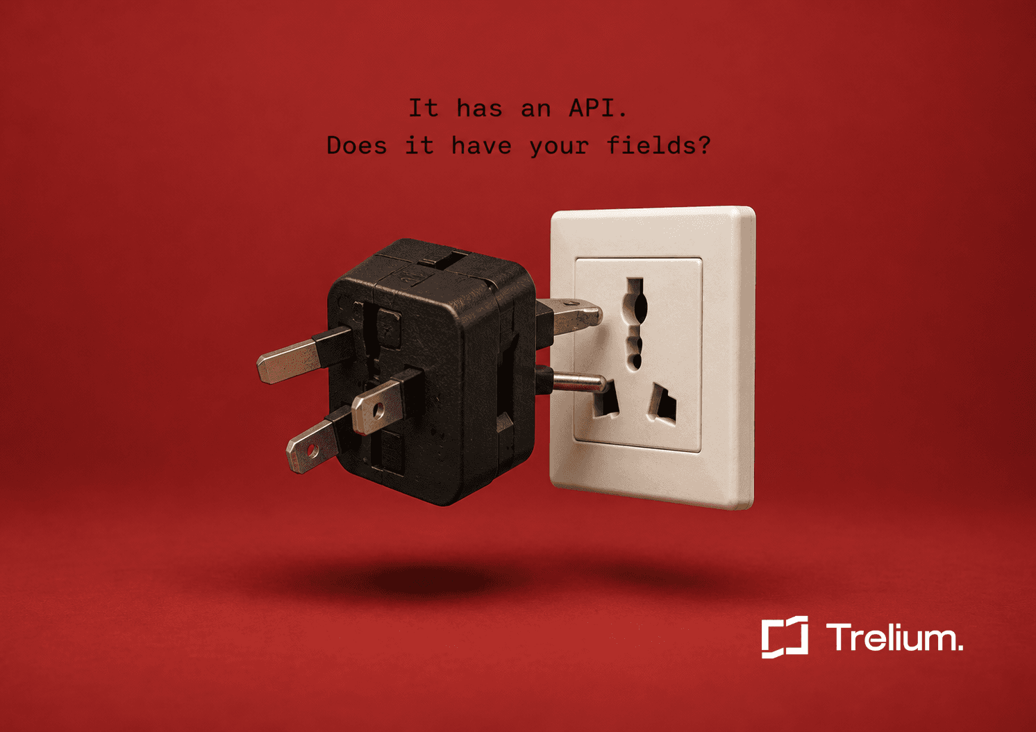 A black universal travel adapter floats half plugged into a beige wall socket with several prongs left outside the holes, against a deep red background.